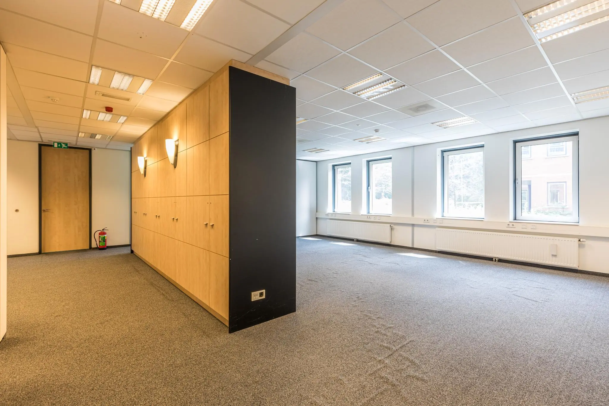 Lichte, lege kantoorruimte aan de Laan Blussé van Oud-Alblas met tapijtvloer, ingebouwde kasten en grote ramen.